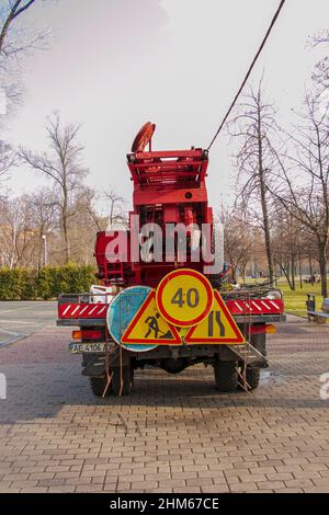 Dnepropetrovsk, Ukraine - 11.22.2021: In einem öffentlichen Park wird ein Mobilkran mit einem orangefarbenen Korb verwendet, um Bäume zu trimmen. Stockfoto