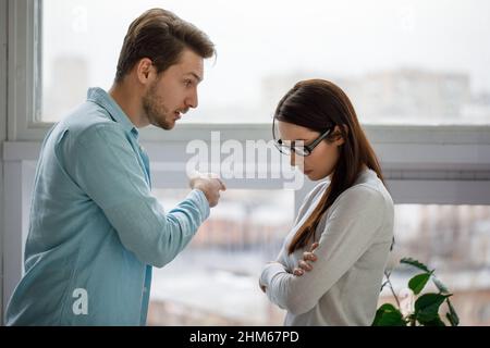 Junges Paar mit Streit-Konflikt, schlechte Beziehungen. Wütende Männer brüllen eine Frau an. Stockfoto