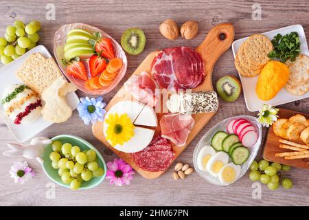 Frühling oder Ostern Thema Charcuterie Tischszene vor einem Holzhintergrund. Verschiedene Vorspeisen mit Käse, Fleisch, Obst und Gemüse. Draufsicht. Stockfoto