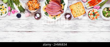 Traditionelles Abendessen mit Osterschinken. Draufsicht oberer Rand auf einem weißen Holzbanner Hintergrund mit Kopierfläche. Schinken, Jakobsmuffel, Gemüse, Eier, Stockfoto