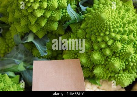 Romanesco Brokkoli zum Verkauf auf einen Markt. Romanesco Brokkoli, Blumenkohl oder Römischen hautnah. Gemüsemarkt. Frisches Gemüse im Korb, darunter ein Blumenkohl und Romanesco Brokkoli. Stockfoto