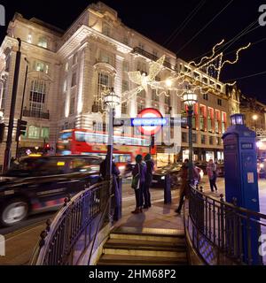 London, Greater London, England, 4th 2022. Januar: Piccadilly Zirkus an einer festlichen Nacht, während die Leute neben dem Eingang der U-Bahn warten, während der Verkehr vorbeizieht. Stockfoto