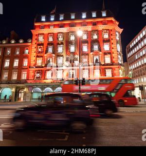 Bus und Taxis fahren am Kaufhaus Fortnum und Mason mit seiner weihnachtlich beleuchteten Fassade am Piccadilly, London vorbei. Stockfoto