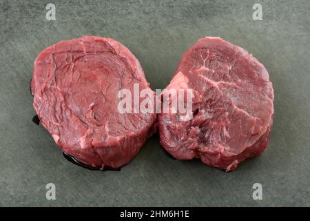 Zwei frische Roh-Rinderfilet-Steaks auf schwarzem Schneidebrett Stockfoto