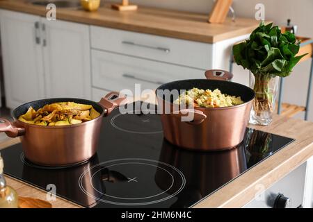 Kochgeschirr mit zubereiteten Speisen auf dem Herd in der Küche Stockfoto