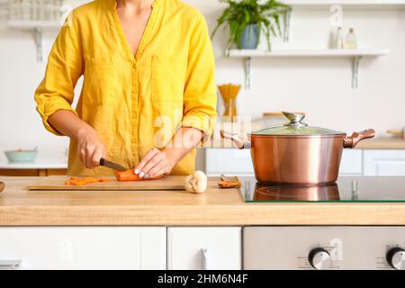 Frau in der Küche Karotten auf Holzbrett schneiden Stockfoto