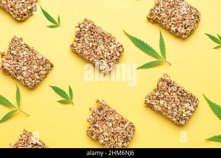 Proteinriegel mit Hanfsamen und Blättern auf gelbem Hintergrund Stockfoto