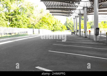 Leerer Parkplatz unter dem Vordach auf grünem Baumhintergrund Stockfoto