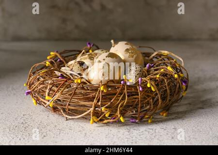 Korbnest mit schönen Ostereiern auf hellem Hintergrund Stockfoto