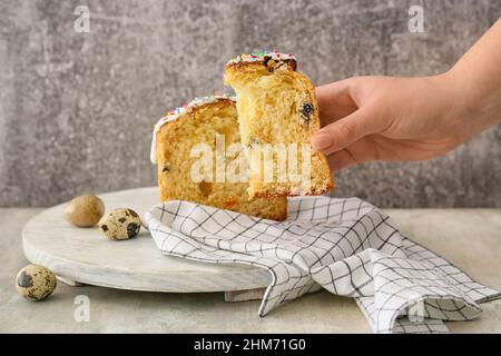 Frau hält ein Stück leckeren Osterkuchen auf grauem Hintergrund Stockfoto