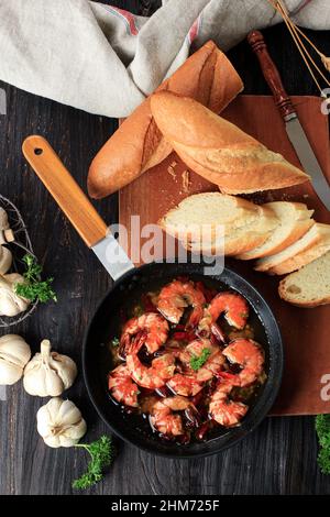 Spanische, gebratene Chili Shrimp Tapas, Gambas al Ajillo. Auch beliebt in Korea. In der Regel mit Baguette oder Spaghetti serviert. Blick von oben auf dem Holztisch Stockfoto