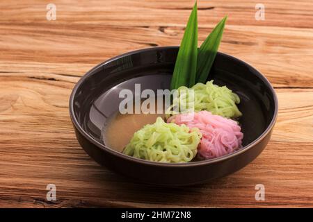 Putu Mayang oder Petulo, indonesischer traditioneller javanischer Snack aus Reismehlsträngen, zusammengerollt zu einem Ball mit Lebensmittelfarbe, serviert mit Kokosnuss Stockfoto