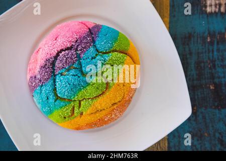 Regenbogen-Concha mit einem Herzen. Mexikanisches süßes Brot mit Regenbogendecke. Stockfoto