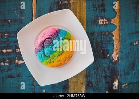 Regenbogen-Concha mit einem Herzen. Mexikanisches süßes Brot mit Regenbogendecke. Stockfoto