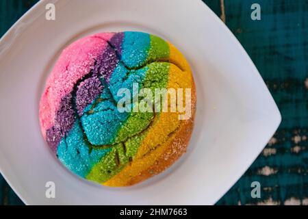 Regenbogen-Concha mit einem Herzen. Mexikanisches süßes Brot mit Regenbogendecke. Stockfoto