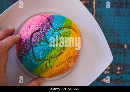 Regenbogen-Concha mit einem Herzen. Mexikanisches süßes Brot mit Regenbogendecke. Stockfoto