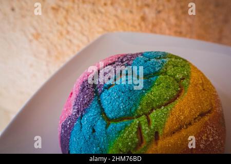 Regenbogen-Concha mit einem Herzen. Mexikanisches süßes Brot mit Regenbogendecke. Stockfoto