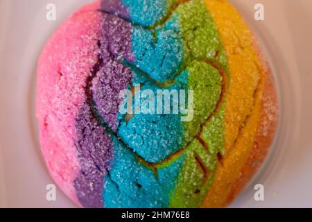 Regenbogen-Concha mit einem Herzen. Mexikanisches süßes Brot mit Regenbogendecke. Stockfoto