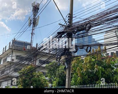 Bangkok, Thailand. 07th. Februar 2022. Kabelgewirr im Zentrum von Bangkok. Strom- und Telefonleitungen sowie Glasfaserkabel werden in Thailand nicht unterirdisch verlegt, sondern erstrecken sich in massiven schwarzen Bündeln von Pol zu Pol. Alte Kabel werden in der Regel nicht entsorgen, aber neue werden einfach hinzugefügt. (To dpa-KORR 'Thailand kurios: Kabelsalat, Fanta am Baum und Füße weg vom Buddha') Quelle: Carola Frentzen/dpa/Alamy Live News Stockfoto