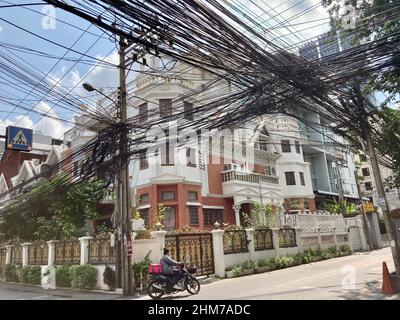 Bangkok, Thailand. 07th. Februar 2022. Kabelgewirr im Zentrum von Bangkok. Strom- und Telefonleitungen sowie Glasfaserkabel werden in Thailand nicht unterirdisch verlegt, sondern erstrecken sich in massiven schwarzen Bündeln von Pol zu Pol. Alte Kabel werden in der Regel nicht entsorgen, aber neue werden einfach hinzugefügt. (To dpa-KORR 'Thailand kurios: Kabelsalat, Fanta am Baum und Füße weg vom Buddha') Quelle: Carola Frentzen/dpa/Alamy Live News Stockfoto