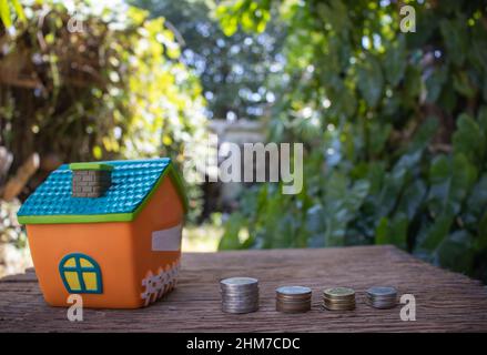 Mini-Haus-Modell und Stapel von Münzen. Risikomanagement für Unternehmen. Immobilieninvestition und Haushypothek Finanzimmobilienkonzept Stockfoto