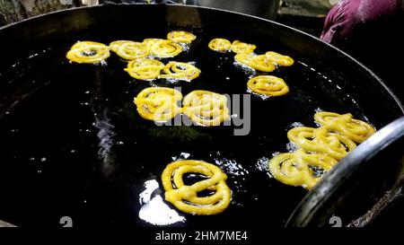 Ein indischer Jalebi, der am Stand in einer Ölpfanne braten wird. Jalebi ist eine berühmte indische Süßigkeit Stockfoto