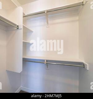 Quadratischer kleiner begehbarer Kleiderschrank mit vertikalen Regalen in der Ecke Stockfoto