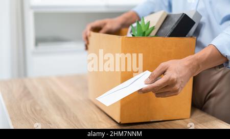 Resignation Konzept der männliche Offizier steht, legt seine Kiste seiner gehört auf den Schreibtisch und übergibt den weißen Brief an jemanden. Stockfoto