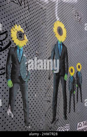 Surrealismus und Business , Sonnenblume Kopf anstelle eines Mannes in einem schwarzen Anzug an der Wand . Stockfoto