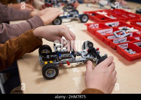 Nahaufnahme eines nicht erkennbaren Jungen, der in der Schule in der Robotik- und Ingenieurklasse ein Elektroauto baut, Kopierraum Stockfoto