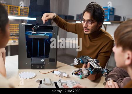 Porträt eines jungen Lehrers, der Kindern im Robotikunterricht in der Schule 3D Drucktechnologien zeigt Stockfoto