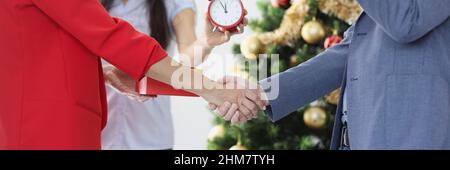 Geschäftsleute schütteln sich die Hände auf dem Hintergrund des Neujahrsbaums Stockfoto