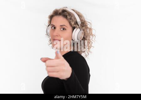 Lächelnde Frau mit Kopfhörern, die auf die Kamera zeigt Stockfoto