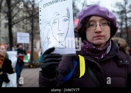 Moskau, Russland. 7th. März 2014 Eine Frau hält während eines Streikens der politischen Partei "Jabloko" auf dem Nowopushkinsky-Platz im Zentrum von Moskau gegen die Militäraktion in der Ukraine ein Anti-Kriegs-Transparent. Die russische Inschrift auf dem Banner bedeutet „Komm zur Vernunft“ Stockfoto