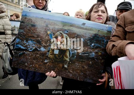 Moskau, Russland. 15th. März 2014 Eine Frau hält ein Banner mit einem Foto des Fotografen Vladimir Vjatkin bei der Aktion "eine Sekunde des Krieges" im Rahmen des Friedensmarsches entlang der Boulevards des zentralen Moskauer, Russland. Während eines marsches gegen den Krieg mit der Ukraine halten die Menschen Fotos berühmter russischer Dokumentarfotografen (Gewinner des World Press Photo) Stockfoto