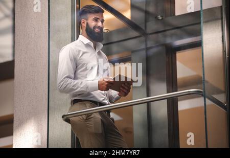 Porträt eines erfolgreichen Geschäftsmannes mit digitalem Tablet im Büro. Technologiekonzept für Geschäftsleute Stockfoto
