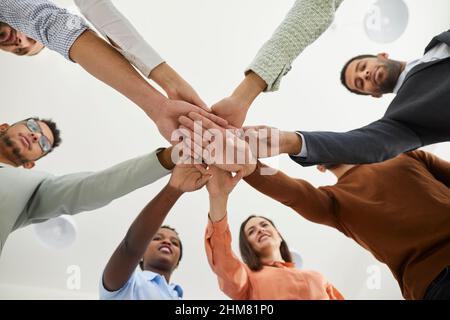 Aufnahme aus der unteren Perspektive eines Teams junger Geschäftsleute, die im Kreis stehen und sich in die Hände greifen Stockfoto