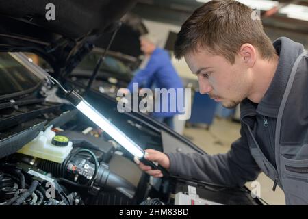 Schüler mit Lehrer, die Reparatur eines Autos während der Lehrzeit Stockfoto