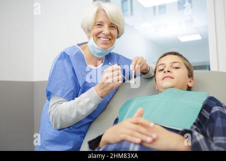 Ältere weibliche Zahnärztin mit einem kleinen Patienten Stockfoto
