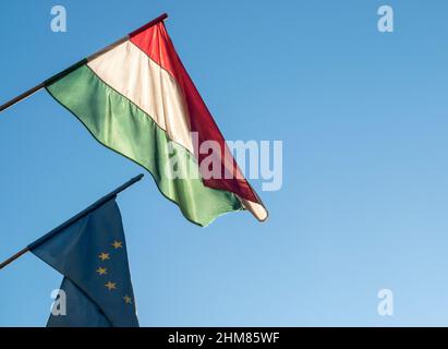 Flaggen Ungarns und der EU oder der Europäischen Union gegen blauen Himmel, Konzeptbild Stockfoto