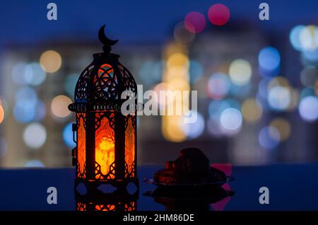 Selektiver Fokus von Laterne und kleinen Teller mit Datteln Frucht mit Wohnung Gebäude Hintergrund für das muslimische Fest des heiligen Monats Ramadan Kareem. Stockfoto