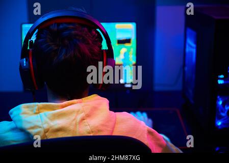 Teenager Junge spielen Computer-Videospiel im dunklen Raum, verwenden neonfarbene rgb mechanische Tastatur, Arbeitsplatz für Cybersport-Gaming, Kinder Spielsucht Stockfoto