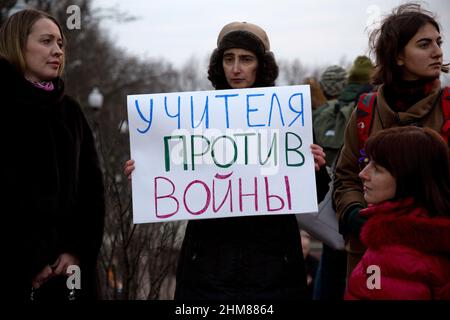 Moskau, Russland. 7th. März 2014 Eine Frau hält während eines Streikens der politischen Partei "Jabloko" auf dem Nowopushkinsky-Platz im Zentrum von Moskau gegen militärische Aktionen in der Ukraine ein Anti-Kriegs-Transparent. Die russische Inschrift auf dem Banner lautet „Lehrer gegen Krieg“ Stockfoto