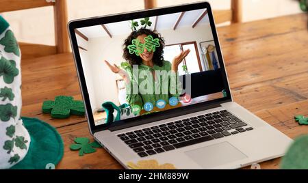 Webcam-Ansicht der kaukasischen Frau mit Schamrock-Brille bei Videoanruf auf Laptop auf Holztisch Stockfoto