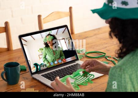 Kaukasische Frau, die eine Schamrock-Brille hält, während sie zu Hause einen Videoanruf auf dem Laptop führt Stockfoto