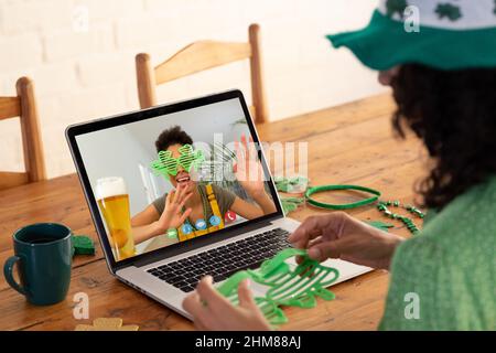 Kaukasische Frau, die eine Schamrock-Brille hält, während sie zu Hause einen Videoanruf auf dem Laptop führt Stockfoto