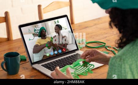 Kaukasische Frau, die eine Schamrock-Brille hält, während sie zu Hause einen Videoanruf auf dem Laptop führt Stockfoto