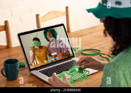 Kaukasische Frau, die eine Schamrock-Brille hält, während sie zu Hause einen Videoanruf auf dem Laptop führt Stockfoto