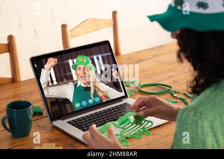 Kaukasische Frau, die eine Schamrock-Brille hält, während sie zu Hause einen Videoanruf auf dem Laptop führt Stockfoto