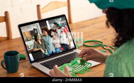 Kaukasische Frau, die eine Schamrock-Brille hält, während sie zu Hause einen Videoanruf auf dem Laptop führt Stockfoto